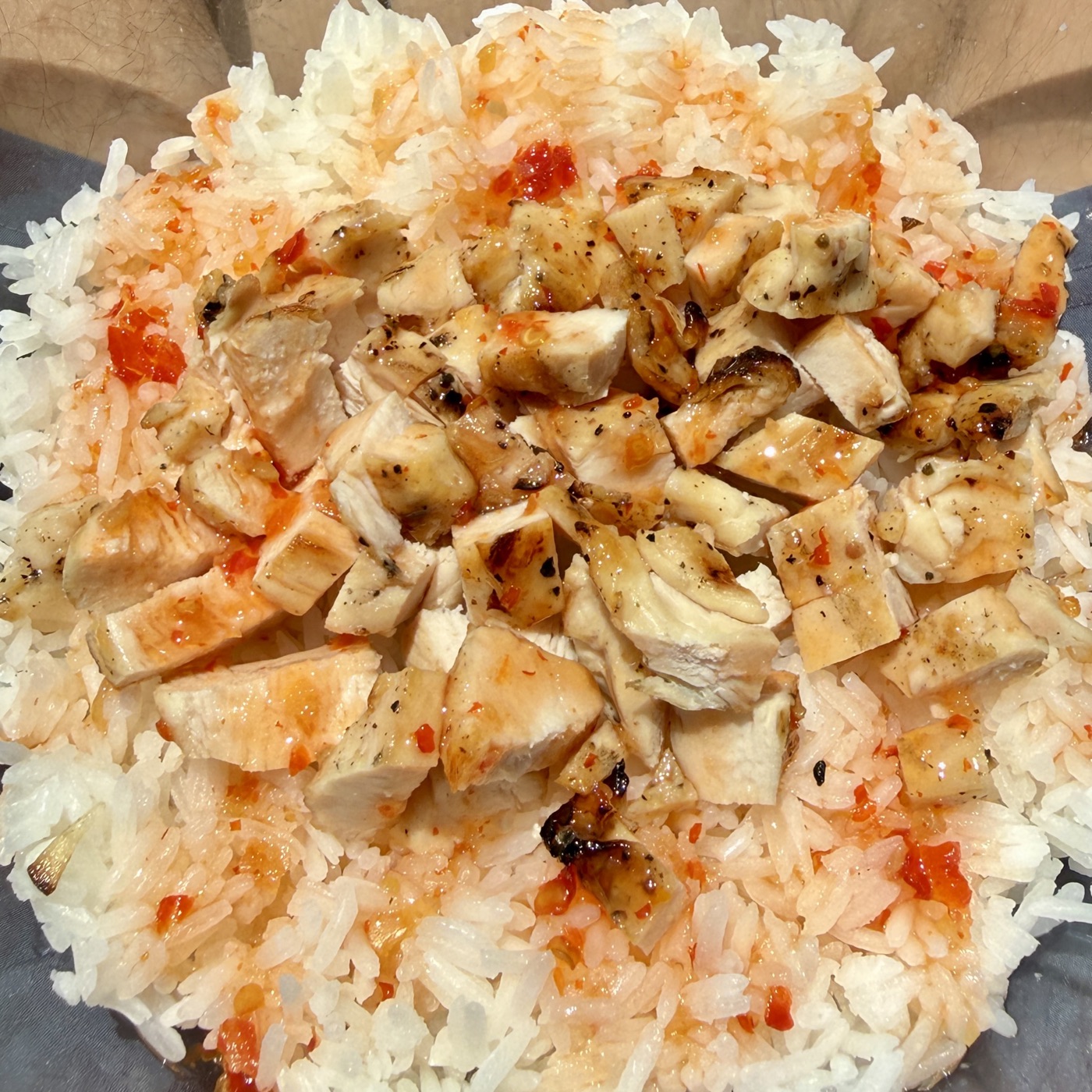 Loading-day lunch: a glass bowl of jasmine rice topped with cubed grilled chicken and sweet chili sauce.